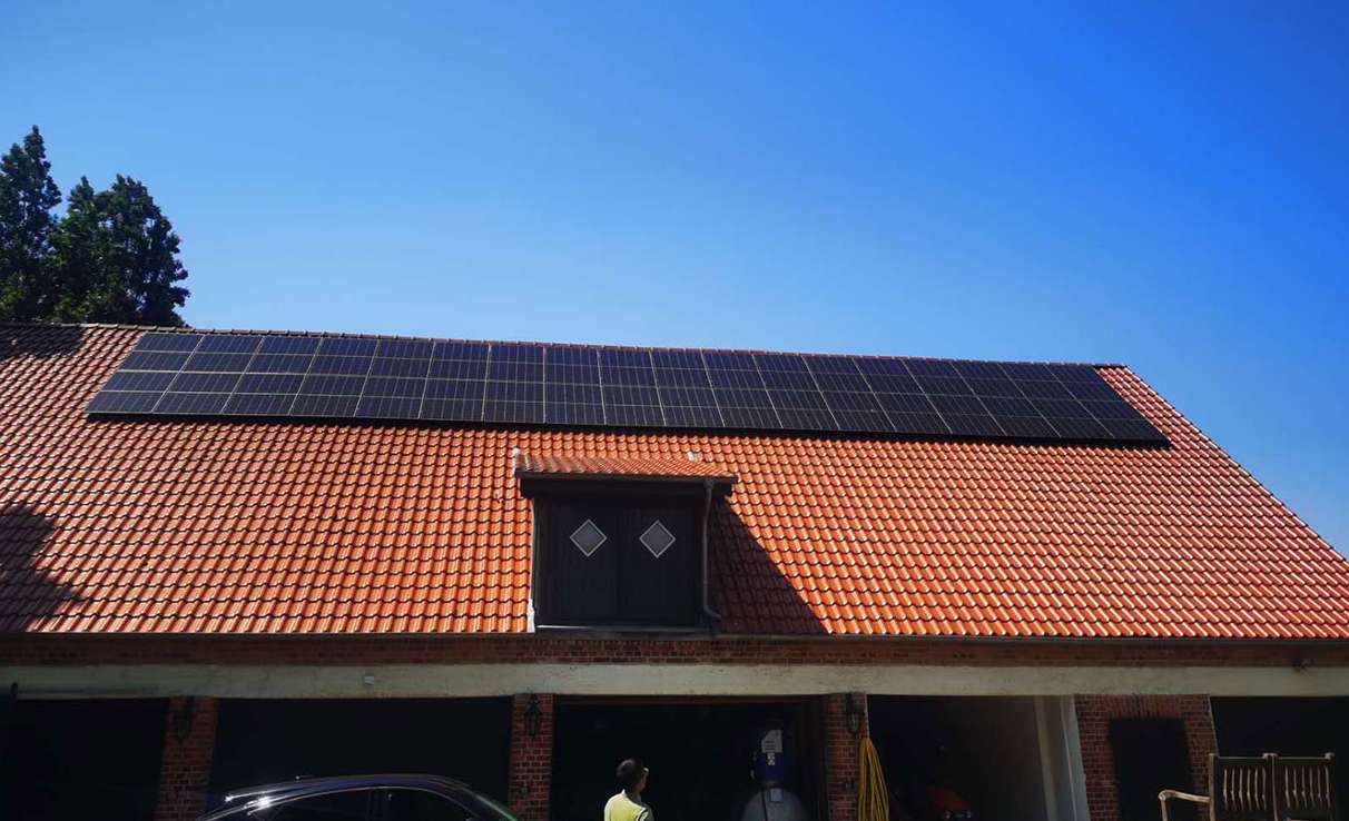 A residential rooftop solar system installed on a red-tiled sloped roof, featuring black monocrystalline panels neatly aligned for optimal sun exposure.