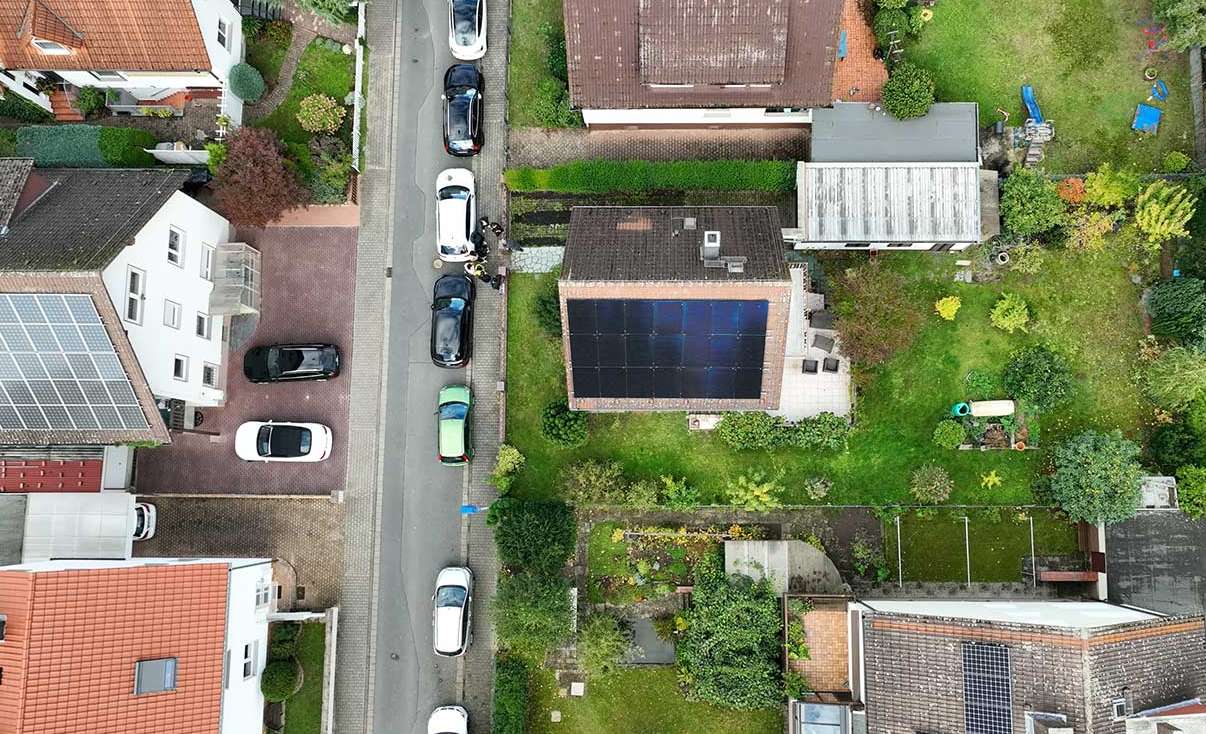 Aerial view of a suburban residential neighborhood with rooftop solar panels installed on multiple houses, showcasing sustainable living in a green environment