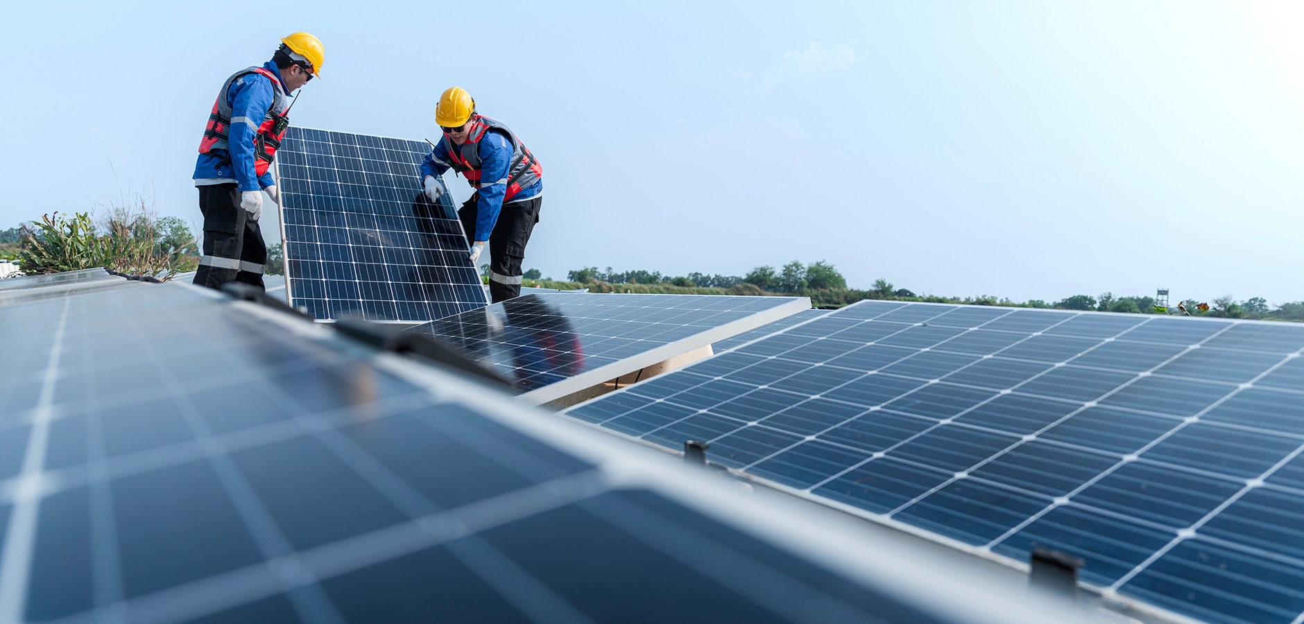 Solavita EPC team members installing Solavita solar panels on a rooftop, showcasing the installation process of solar modules. The workers are wearing safety gear, including helmets and high-visibility vests, as they carefully position and secure the solar panels in place for efficient energy generation