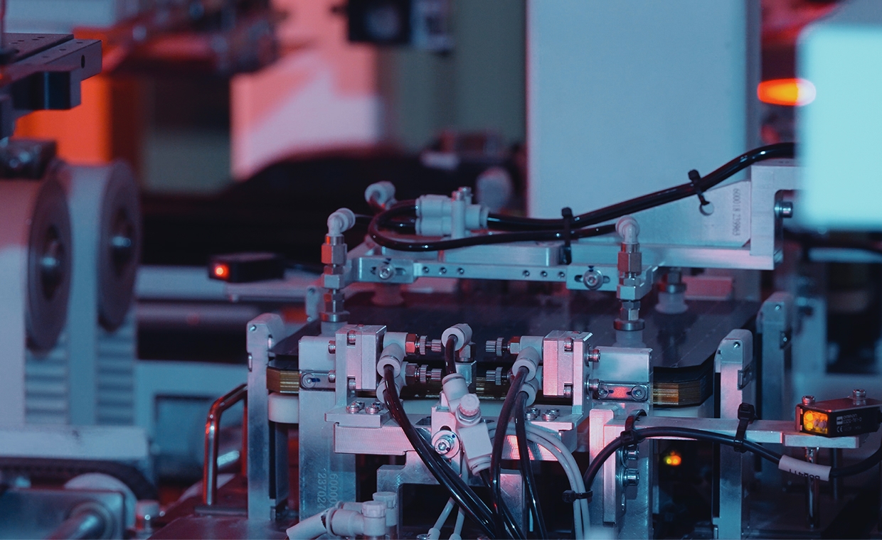 Close-up of automated machinery for solar cell manufacturing with electrical wiring and robotic components