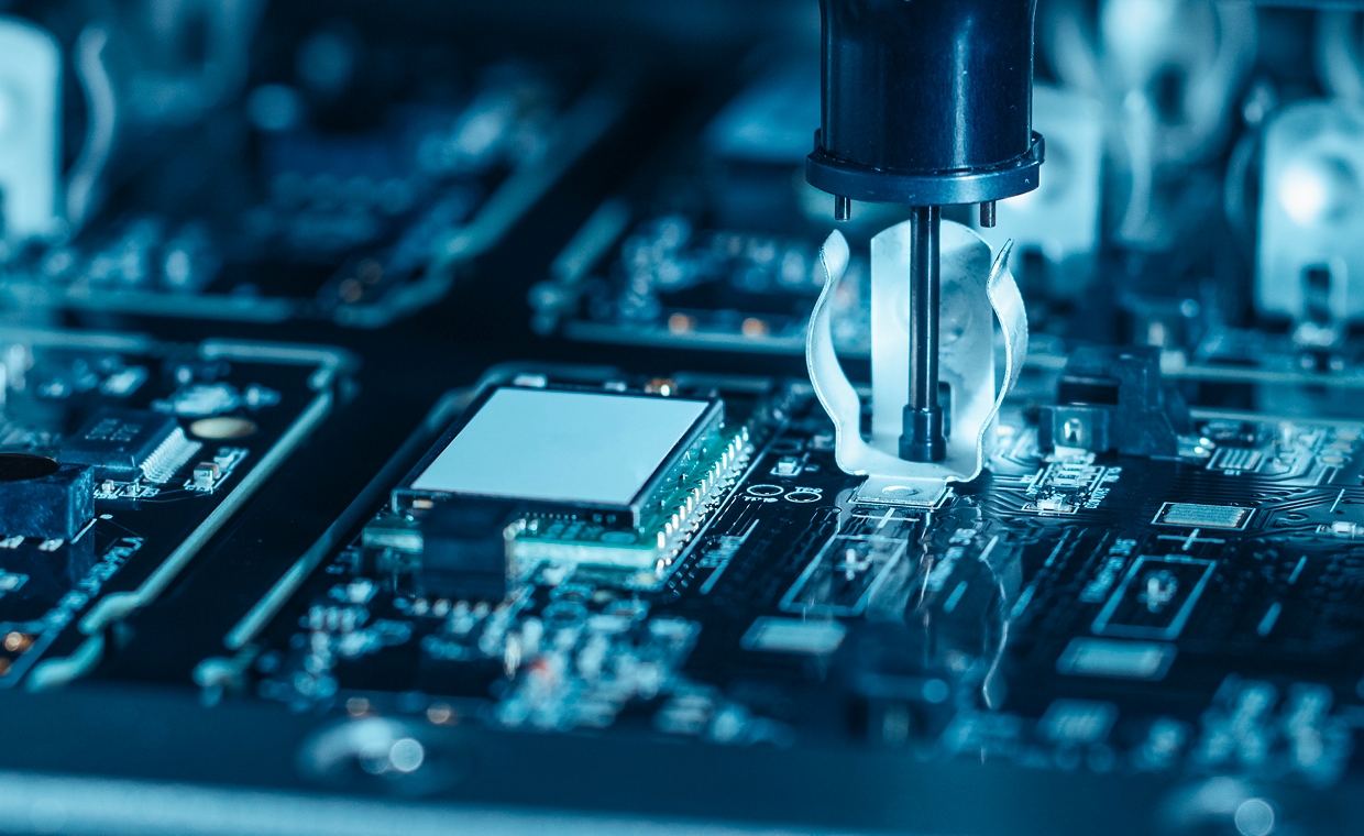 Automated robotic arm assembling components on printed circuit board in electronics manufacturing factory